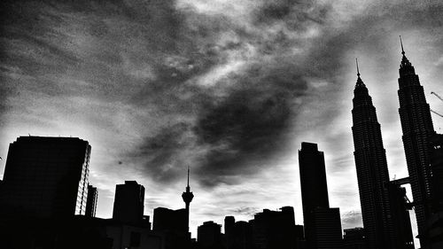Low angle view of buildings in city against cloudy sky