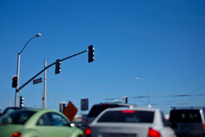 Cars by road signal against blue sky