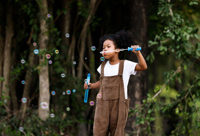 Full length of boy holding bubbles while standing outdoors