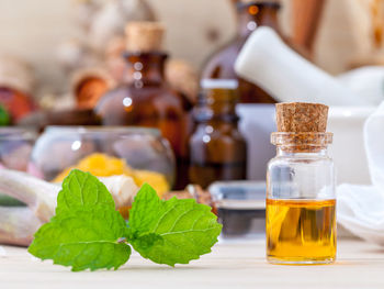 Close-up of herb and bottle on wooden table