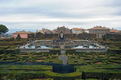 Buildings in garden against cloudy sky