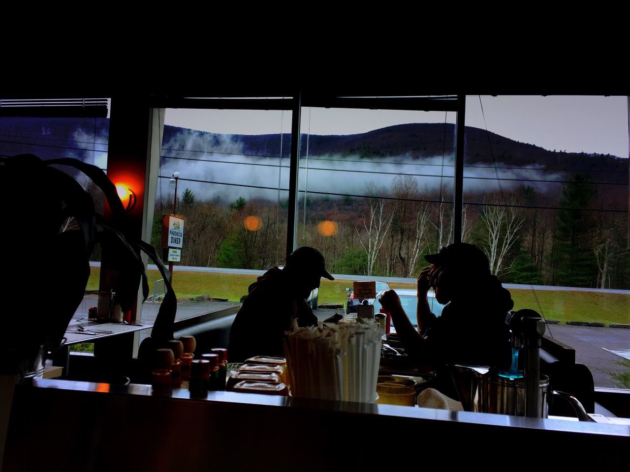 indoors, window, men, sitting, glass - material, lifestyles, table, leisure activity, transparent, restaurant, food and drink, chair, person, rear view, drink, silhouette, glass