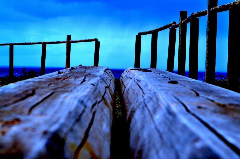 wood - material, wooden, pier, railing, surface level, selective focus, blue, metal, fence, sky, wood, boardwalk, water, nature, plank, close-up, diminishing perspective, day, outdoors, sunlight