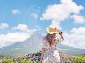 Rear view of woman standing on mountain against sky