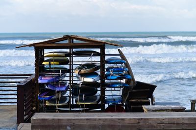 Deck chairs on beach against sky