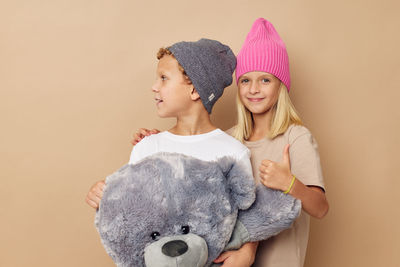 Portrait of young woman with stuffed toy against wall