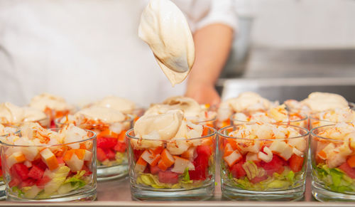 Glasses with chopped prawns with watermelon, crab sticks, lettuce, pink sauce and parsley