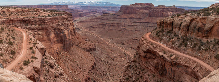 Panoramic view of rocky canyon with snow capped mountains in background