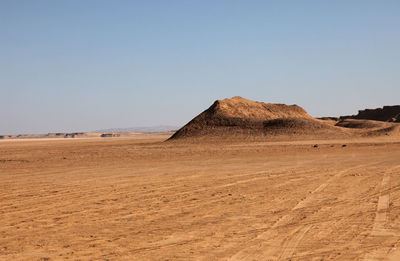 Rock on arid landscape against clear sky