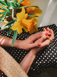 Midsection of woman sitting by yellow flowers