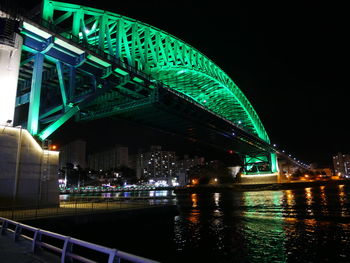 Illuminated bridge over river against sky at night
