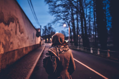 Rear view of person walking on road in city