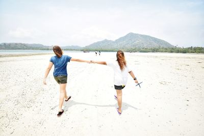 Rear view of women on beach against sky