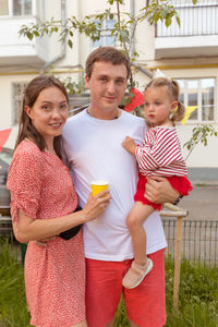 Positive young family with kid standing on street