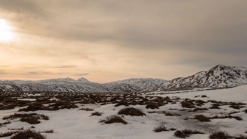 Scenic view of snow covered mountains against cloudy sky