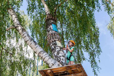 Adventure climbing high wire park - people on course in mountain helmet and safety equipment