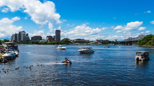 Boats in river against buildings in city