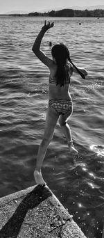 Rear view of woman with arms raised in swimming pool