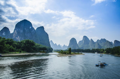 Scenic view of boats in river against cloudy sky