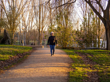 Full length portrait of senior woman walking on footpath in park