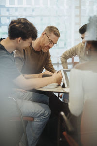 Mature professor assisting students in classroom at university