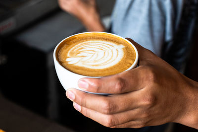 Midsection of man holding cappuccino
