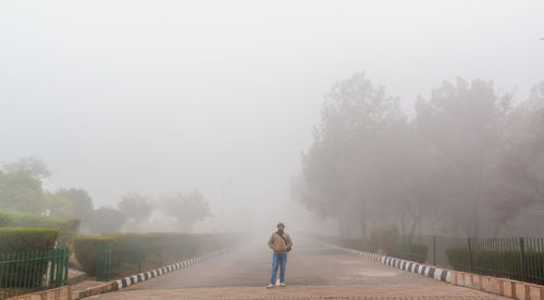 Full length of man standing in park during foggy weather