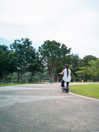 A nice asian young girl is riding a scooter. active leisure in the park. children's sports