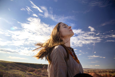 Female tourist with eyes closed standing against sky at petrified forest, national park, arizona, usa