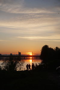 Silhouette people standing on land against sky during sunset