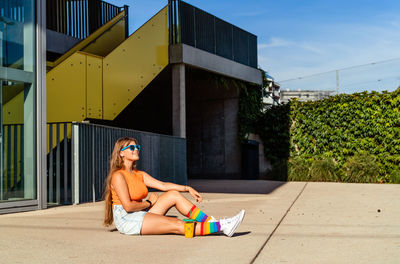 Young happy smiling teen girl wearing bright colorful top and rainbow pride socks enjoying sun 
