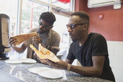 Two young men eating pizza.