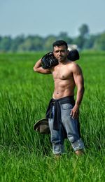 Full length of shirtless man photographing on field