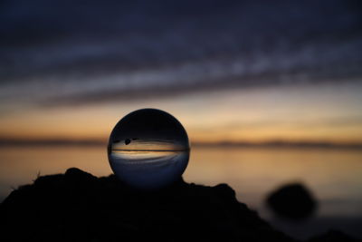 Close-up of rock on sea against sky during sunset