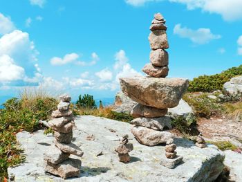 Stack of stones on rock against sky