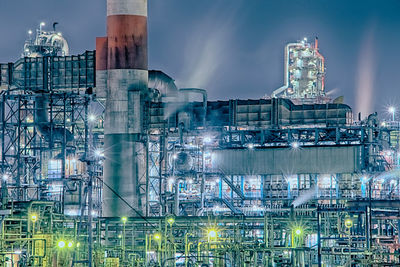 Low angle view of illuminated factory against sky at night