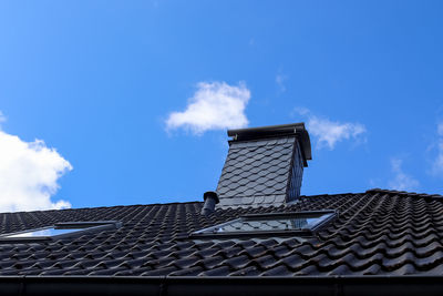 Roof window in velux style with black roof tiles