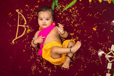 Cute indian boy dresses as lord rama with bow and flowers from top angle