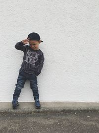 Full length of boy standing against white wall