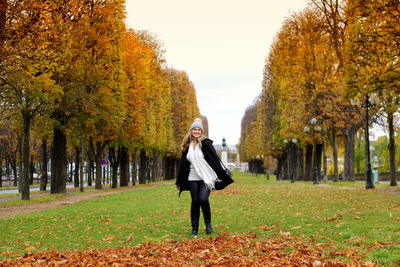 Full length of young woman standing on field during autumn