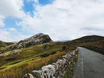 Scenic view of road by mountain against sky