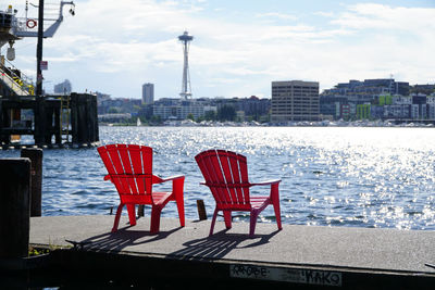 Empty chairs and table by buildings in city against sky