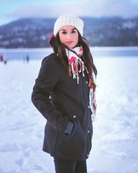 Portrait of beautiful woman standing on snow covered field