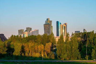 Trees and buildings against clear sky