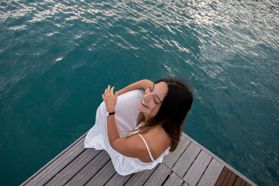 High angle view of woman sitting on wood by sea