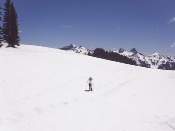 Mature woman standing snow covered mountain against blue sky during sunny day