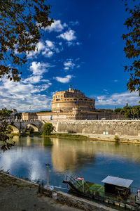 Buildings at waterfront against cloudy sky