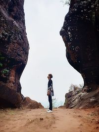 Man standing on rock against sky