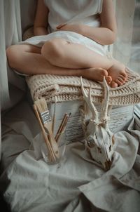 Midsection of woman sitting on bed at home