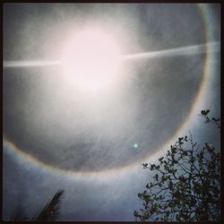 Low angle view of sun shining through clouds